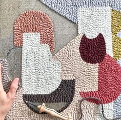 a person is working on a rug with scissors and threading needles in front of it