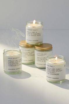 three candles with labels on them sitting next to each other in front of a white background