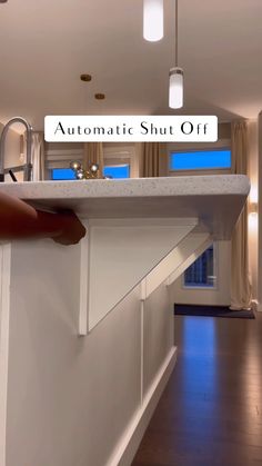 an automatic shut off sign above a kitchen sink in a house with wood floors and white walls