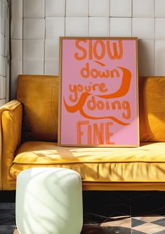 a yellow couch sitting next to a pink sign that says slow down you're doing fine