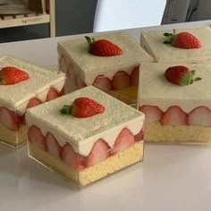 four pieces of cake sitting on top of a table with strawberries in the middle