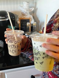 two people are holding up cups with straws in their hands and writing on them