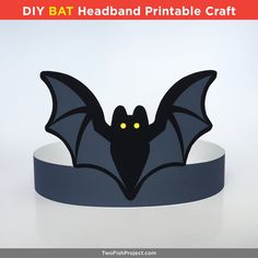 a paper bat headband is shown with yellow eyes and black wings, on a white background