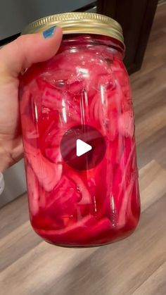 a person holding a jar filled with red liquid