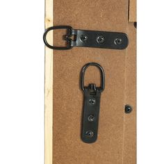 a pair of black hooks are attached to a cork board with a clip on it