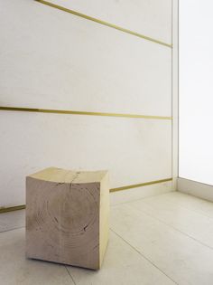 a block of wood sitting on the floor in front of a wall with gold lines