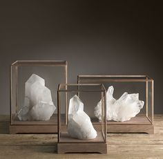 three glass boxes filled with white rocks sitting on top of a wooden table next to each other