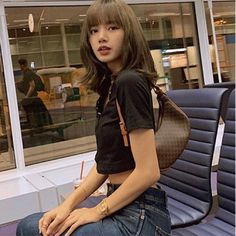 a young woman sitting on top of a bench next to a blue chair in an airport