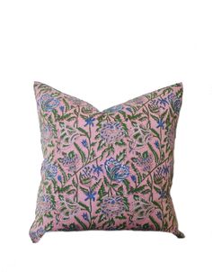 a pink pillow with blue and green floral designs on the front, against a white background