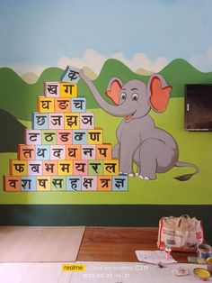 an elephant is playing with blocks in front of a wall painted with the alphabets