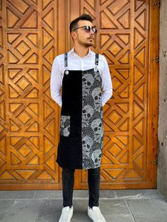 a man standing in front of a wooden door wearing an apron with skulls on it