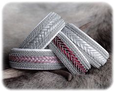 three silver bracelets with red and white braiding