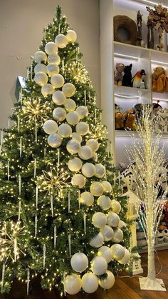 two christmas trees decorated with white balls and lights