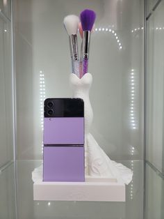 two makeup brushes and a cell phone in a display case