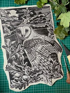 an owl sitting on top of a piece of paper next to scissors and some leaves