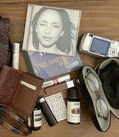 an assortment of personal items laid out on top of a wooden table next to a book