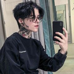 a young man with black hair and tattoos taking a selfie in front of a mirror