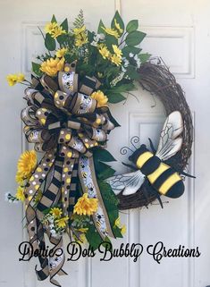 a yellow and black wreath with two bees on it next to a white front door