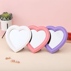 three heart shaped mirrors sitting on top of a table next to a potted plant