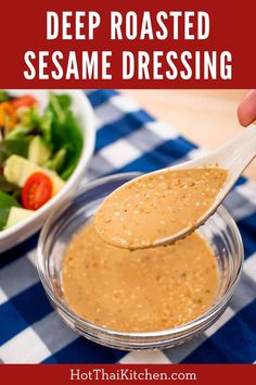 a spoon full of dressing being held over a bowl with salad in it and the words deep roasted sesame dressing