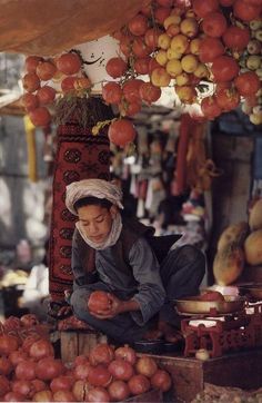 a man sitting on the ground in front of some fruit