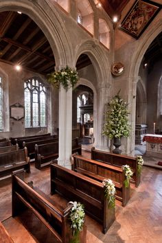 the inside of a church with pews and flowers in vases on each side