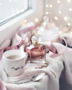 a bottle of perfume sitting on top of a table next to a cup and saucer