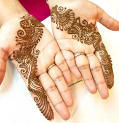 two hands with henna designs on them, one is holding the other's hand