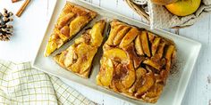 sliced apple pie on a white plate next to some cinnamon sticks and apples in a basket