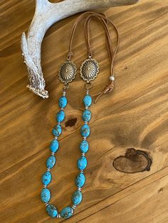 "Southwestern silver concho necklace with luscious blue turquoise beads suspending from adjustable light brown leather lace. These awesome conchos have delicate scalloped edges with an \"Old West\" design giving it a vintage but feminine touch. They are upcycled from a southwestern concho belt. Silver daisy spacers beads separate the turquoise. Tied to the conchos are light brown suede lace. Western design silver bead slides to adjust to your desired length. Silver metal conchos - NOT sterling s Western Jewelry With Adjustable Length For Western-themed Events, Western Style Adjustable Jewelry For Western-themed Events, Southwestern Blue Concho Necklace, Western Blue Concho Necklace, Southwestern Style Blue Concho Necklace, Blue Western Style Concho Necklace, Western Jewelry With Adjustable Length For Festivals, Western Style Adjustable Jewelry For Festivals, Western Style Jewelry With Adjustable Length For Festivals