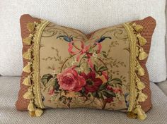 a decorative pillow with flowers on it sitting on a couch in front of a white wall