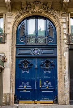 an old building with a blue door and ornate iron work on the front entryway