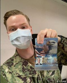 a man wearing a face mask and holding up a card with an eagle on it