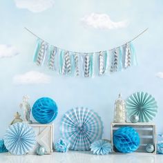 blue and white decorations are on display in front of a wall with clouds above it