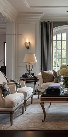 a living room with couches, chairs and tables in front of two large windows