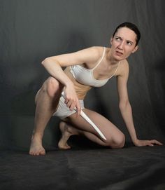 a woman kneeling down with a white frisbee in front of her and black background