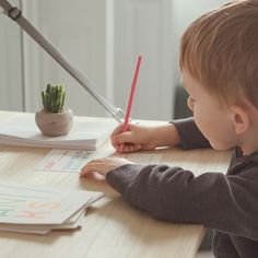 a young boy sitting at a table with a pencil in his hand