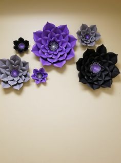 five paper flowers arranged on a wall