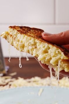 a person holding up a piece of food with cheese and sauce on top of it