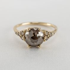 a close up of a ring on a white surface with a brown diamond in the middle