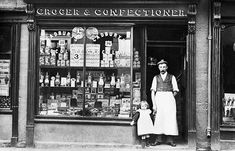 an old black and white photo of two people in front of a store