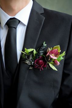 a man wearing a suit and tie with flowers on it's lapel pin