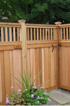 a wooden fence is shown with flowers in the foreground