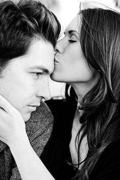 a man and woman kissing each other in black and white