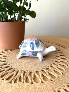 a turtle figurine sitting on top of a table next to a potted plant