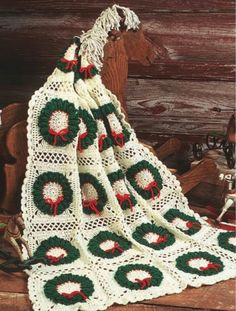 a crocheted christmas blanket sitting on top of a wooden bench