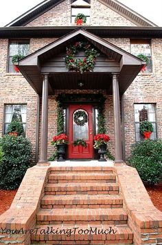 a red front door with wreaths on it and steps leading up to the house