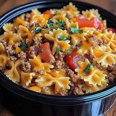 a black bowl filled with pasta and meat