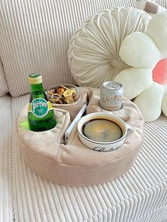 a bottle of beer sitting on top of a couch next to a bowl of food