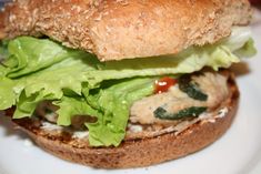 a sandwich with lettuce, tomato and chicken on a white breaded bun